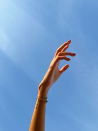 Cropped hand against blue sky