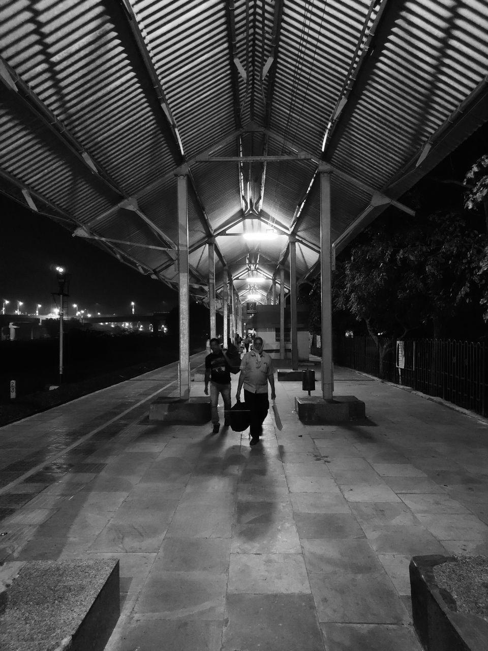 REAR VIEW OF MAN AND WOMAN WALKING IN ILLUMINATED UNDERGROUND