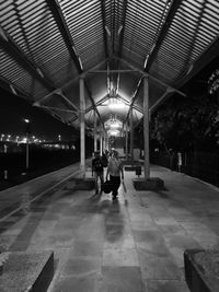 Rear view of woman walking on illuminated corridor