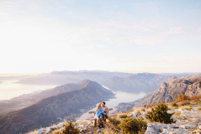 Couple sitting on bench against landscape