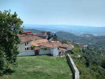 Houses by trees and buildings against sky