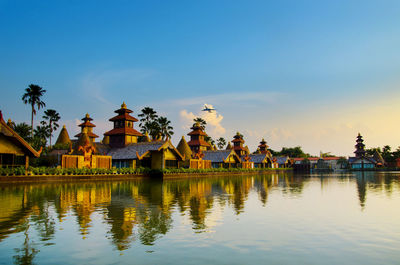 Panoramic view of lake by building against sky during sunset