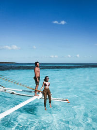 Full length of friends on sea against blue sky