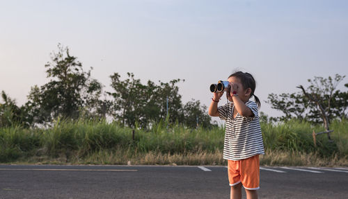 Rear view of young woman standing against sky