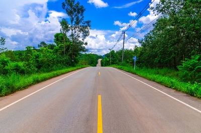 Road amidst plants and trees against sky