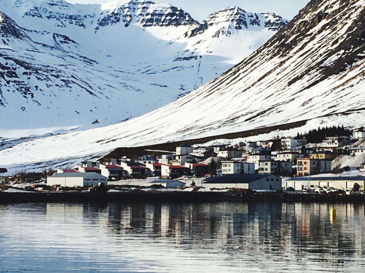 REFLECTION OF HOUSES AND SNOWCAPPED MOUNTAIN IN WINTER