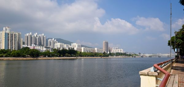 City by river and buildings against sky