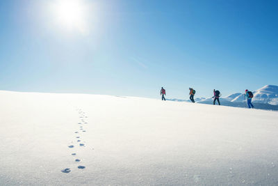 People on snowy landscape against clear blue sky