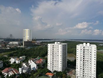 Modern cityscape by sea against sky