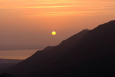 Scenic view of silhouette mountains against orange sky