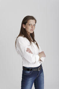Portrait of young woman standing against white background