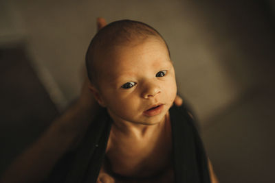 Cropped hands of father carrying newborn daughter at home