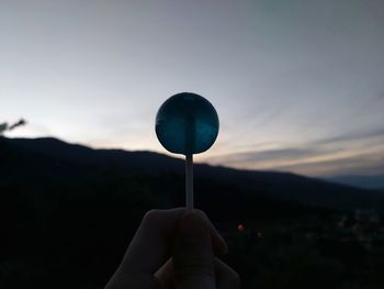 Person holding umbrella against sky during sunset