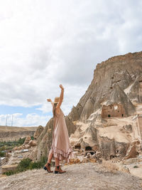 Rear view of woman standing on rock against sky