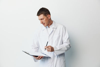 Doctor standing against white background