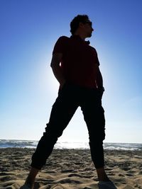 Man standing at beach against clear sky