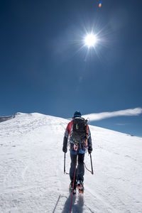 Rear view of people skiing on snowcapped mountain against sky