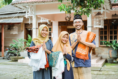 Portrait of smiling family greeting outside house