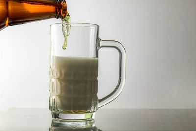 Close-up of drink in glass on table against white background