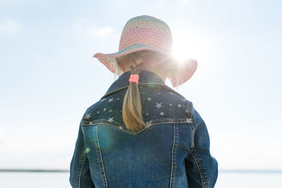 Rear view of girl standing by sea