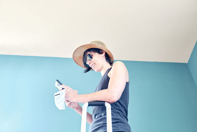 Woman holding umbrella while standing on mobile phone