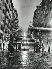 Illuminated building by street against sky at night