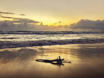 Silhouette person on beach against sky during sunset