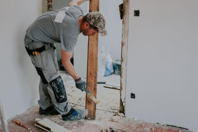 A man working with a crowbar in a doorway.