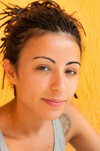 Portrait of a beautiful young woman with pigtails hairstyle, on the yellow background