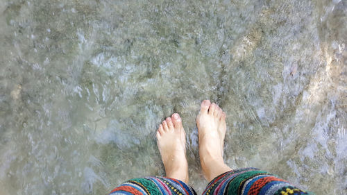 Low section of person standing in sea