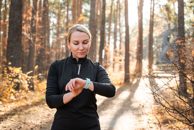 Young man suffering from mobile phone while standing in forest