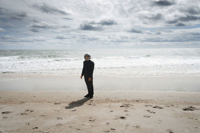 Astronautic man wearing space helmet while standing on sea shore