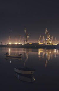 Boats moored at harbor against sky at night