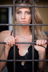 Portrait of young woman seen through metal grate