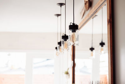 Close-up of light bulbs hanging from window at home