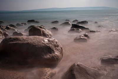 Rocks on sea shore against sky