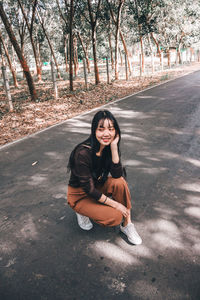 Portrait of young woman sitting on road