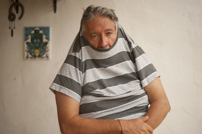 Portrait of man standing against wall at home