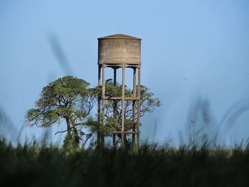 Water tower on field against sky