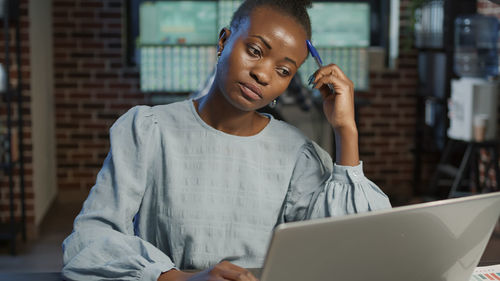 Portrait of young woman using laptop while sitting in cafe