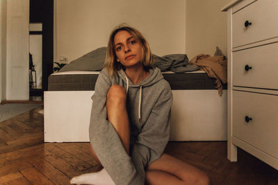 Portrait of woman sitting on floor at home