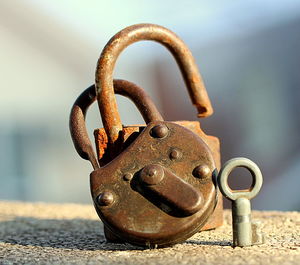 Close-up of rusty padlocks with key on retaining wall
