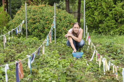 Full length of a smiling young woman sitting on plants