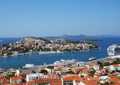 Aerial view of townscape by sea against clear sky