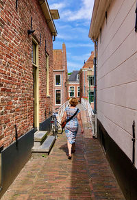 Rear view of woman in summer dress walking through an old town alley