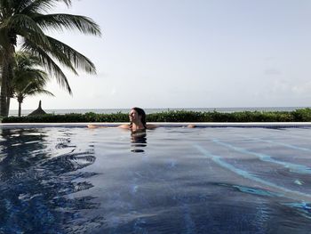 Woman swimming in infinity pool in mexico 