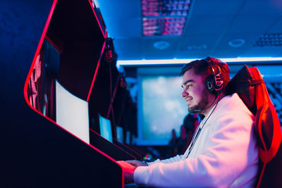 Side view of smiling young man playing video game