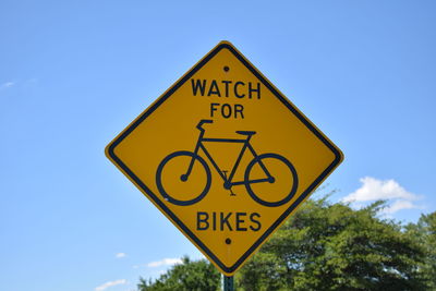 Low angle view of road sign against blue sky