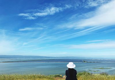 Rear view of man looking at sea against sky
