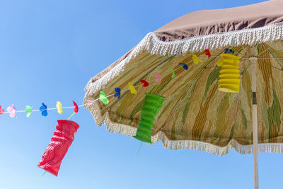 Low angle view of decorations and parasol against clear sky